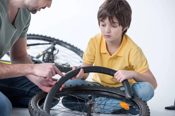 Hijo y padre reparando bicicleta - foto de stock