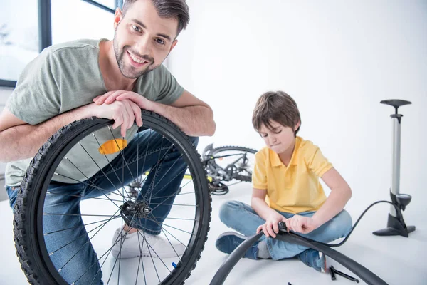 Hijo y padre reparando bicicleta - foto de stock