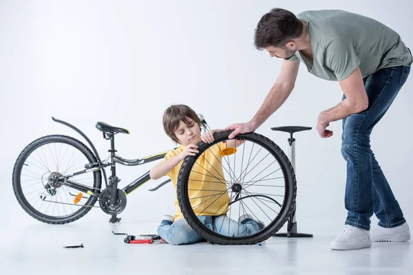Hijo y padre reparando bicicleta - foto de stock