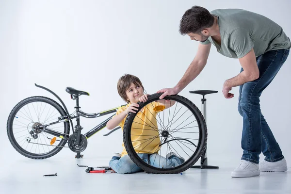 Hijo y padre reparando bicicleta - foto de stock