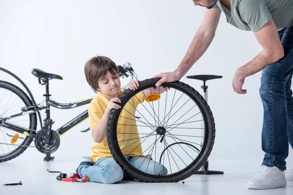 Hijo y padre reparando bicicleta - foto de stock