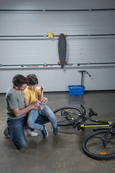 Father putting patch on son — Stock Photo