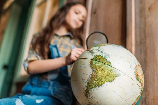 Girl with magnifying glass and globe — Stock Photo