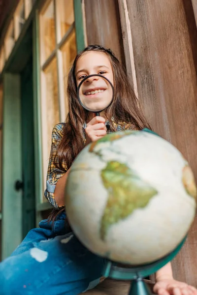 Fille avec loupe et globe — Photo de stock