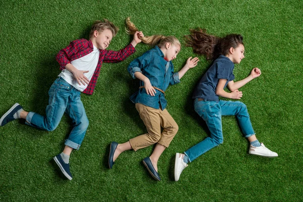 Niños acostados en la hierba - foto de stock