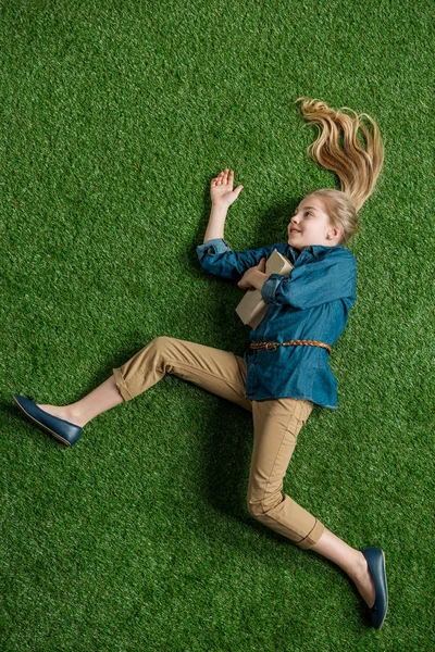 Ragazza con libro sdraiato sull'erba — Foto stock