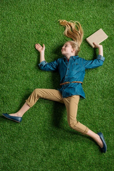 Mädchen mit Buch auf Gras liegend — Stockfoto