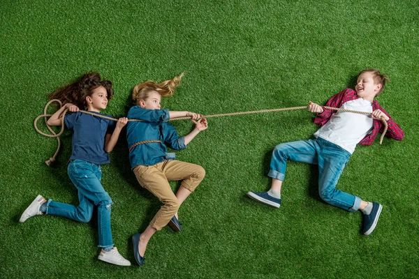 Niños jugando tirón de la guerra - foto de stock