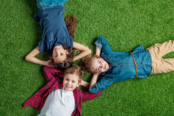 Niños acostados en la hierba - foto de stock