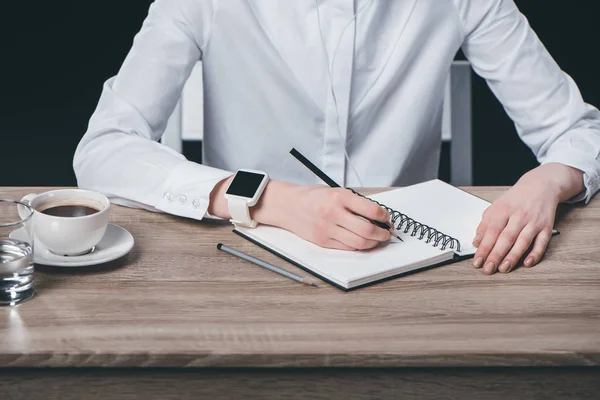 Frau sitzt am Tisch und macht sich Notizen — Stockfoto