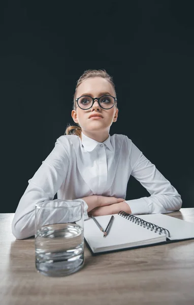 Mujer con anteojos sentada a la mesa - foto de stock