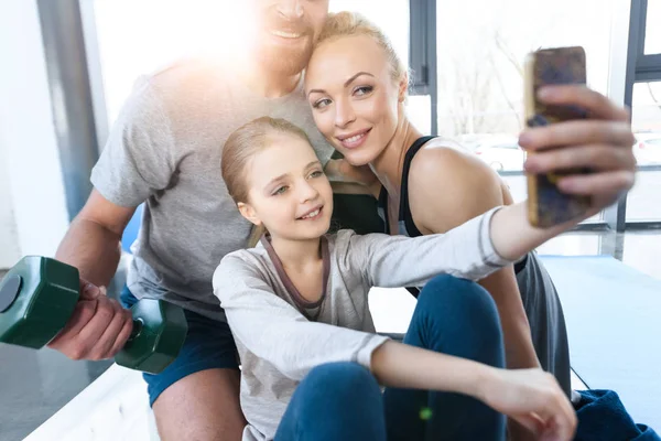 Girl taking self portrait with parents at fitness center — Stock Photo