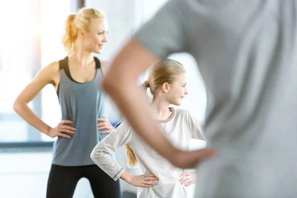 Jeune femme et fille mignonne faisant de l'exercice avec l'entraîneur au studio de fitness — Photo de stock