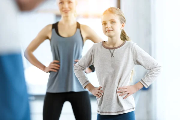 Young woman and cute girl exercising with coach at fitness studio — Stock Photo