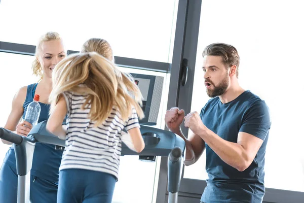 Parents supporting daughter workout on treadmill — Stock Photo