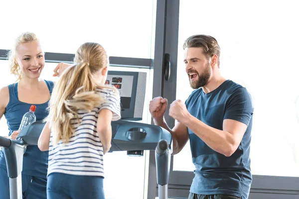 Parents supporting daughter workout on treadmill — Stock Photo