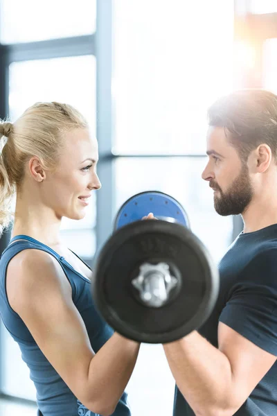 Coppia amorevole esercizio insieme con bilanciere in palestra — Foto stock