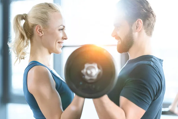 Loving couple exercising together with barbell at gym — Stock Photo