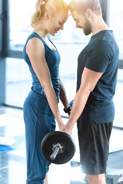 Loving couple exercising together with barbell at gym — Stock Photo