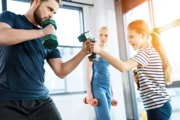 Happy family exercising with dumbbells at fitness studio — Stock Photo