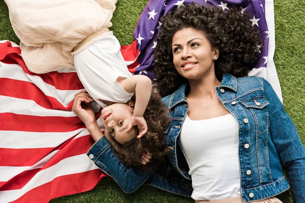 Woman with daughter on american flag — Stock Photo