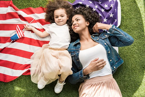 Mujer con hija en bandera americana - foto de stock