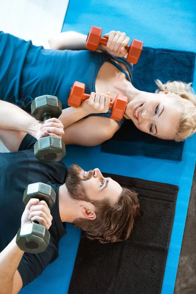 Casal de jovens fitness pessoas se exercitando com halteres no estúdio de fitness — Fotografia de Stock