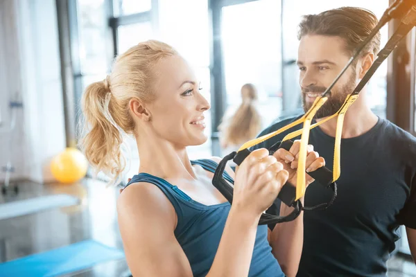 Coach talking with blonde fitness woman training with trx fitness straps — Stock Photo