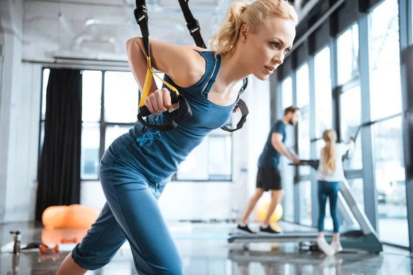 Blonde Fitness-Frau trainiert mit trx Fitnessbändern — Stockfoto