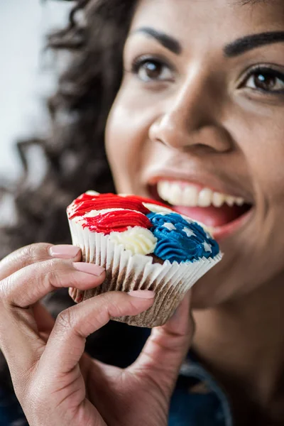 Chica americana morder cupcake - foto de stock