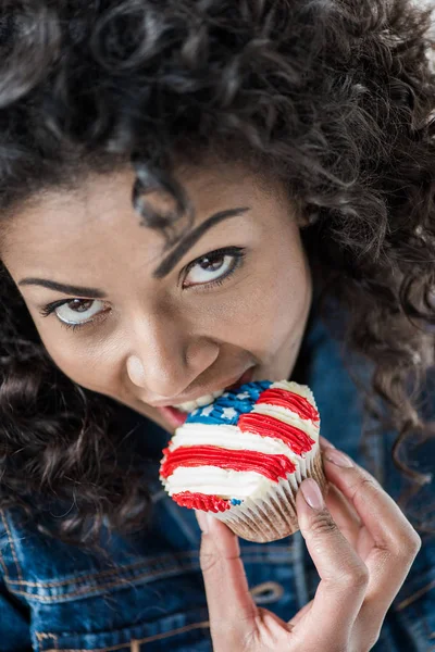 Chica americana morder cupcake - foto de stock