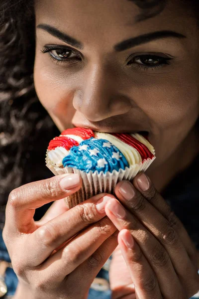 Fille américaine mordre cupcake — Photo de stock