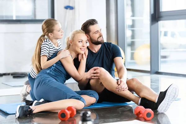 Retrato de la familia feliz sentado en la estera en el gimnasio - foto de stock