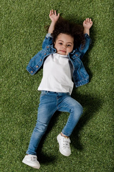 Curly girl resting on lawn — Stock Photo