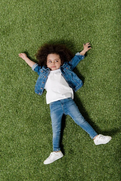 Menina encaracolado descansando no gramado — Fotografia de Stock