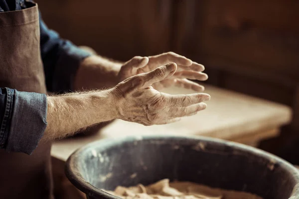 Gros plan des mains masculines de potier prenant l'argile d'un bol — Photo de stock