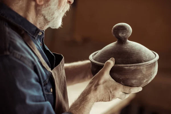 Senior potter in apron examining ceramic bowl at workshop — Stock Photo