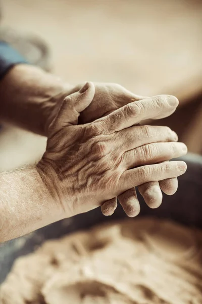 Nahaufnahme männlicher Töpferhände, die Ton aus einer Schüssel nehmen — Stockfoto