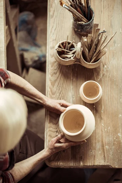 Close up of female hands examining ceramic bowl at workshop — Stock Photo