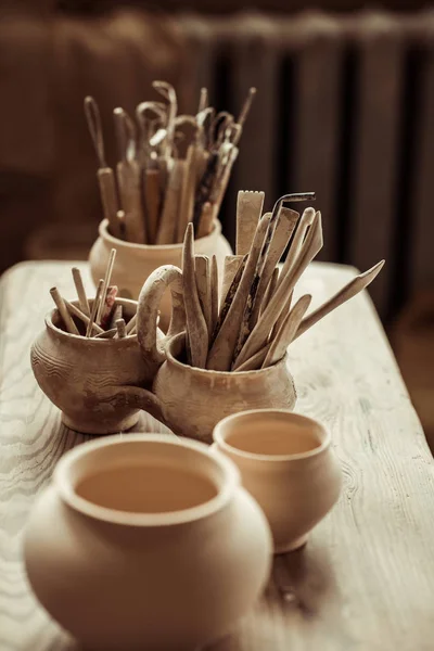 Gros plan des pinceaux avec des outils de poterie dans des bols sur la table — Photo de stock