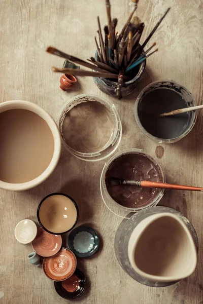 Close up de pincéis de tinta com ferramentas de cerâmica em tigelas na mesa — Fotografia de Stock