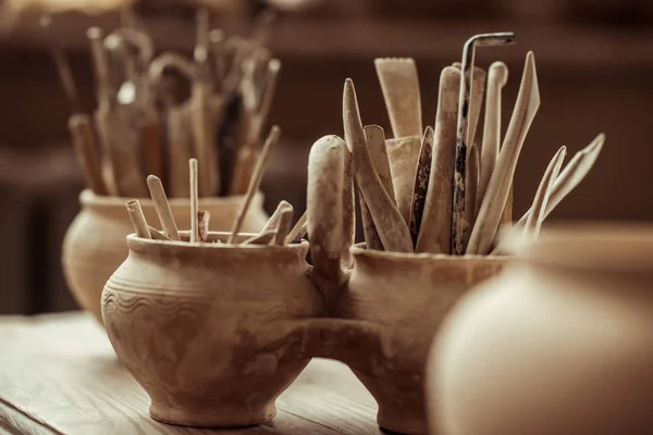 Close up of paint brushes with pottery tools in bowls on table — Stock Photo