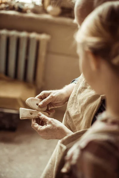 Close up of senior potter showing details to his granddaughter while standing at workshop — Stock Photo