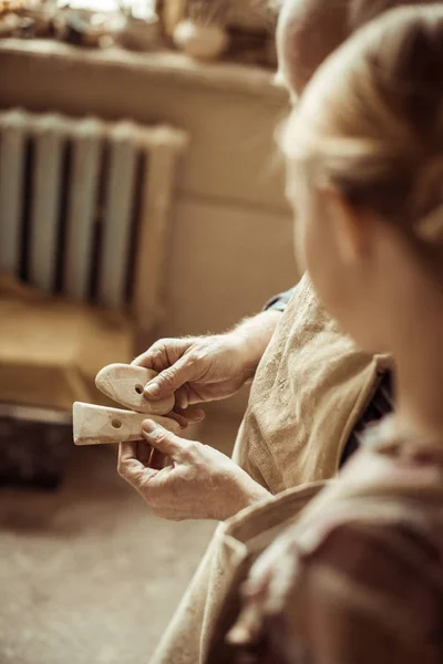 Gros plan de potier senior montrant des détails à sa petite-fille alors qu'elle se tenait debout à l'atelier — Photo de stock