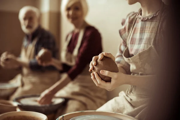 Geschnittenes Bild von Großmutter und Großvater mit Enkelin beim Töpfern in der Werkstatt — Stockfoto