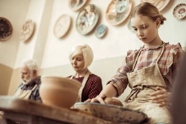 Abuela y abuelo con nieta haciendo cerámica en el taller - foto de stock