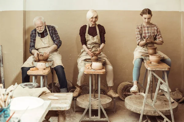 Бабуся і дідусь з онукою роблять кераміку в майстерні — стокове фото
