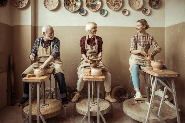 Abuela y abuelo con nieta haciendo cerámica en el taller - foto de stock