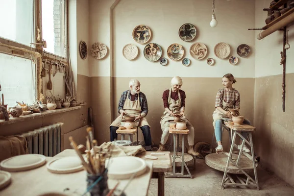 Бабуся і дідусь з онукою роблять кераміку в майстерні — стокове фото