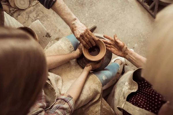 Overhead view of little girl making pottery on wheel with help of grandparents at workshop — Stock Photo